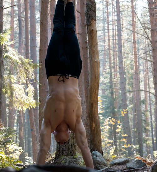 Man performing a controlled strength exercise in a dark, minimalist environment.